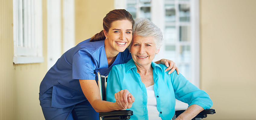 Nurse leaning down with her arms around a patient