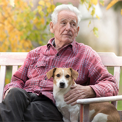 elderly man sitting holding a dog