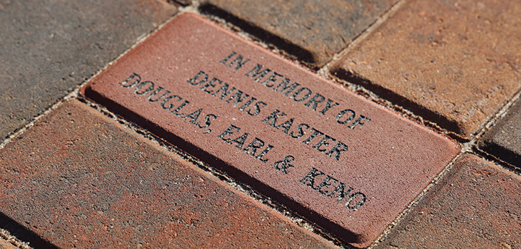 A brick in the cobblestone that reads in memory of Dennis Kaster Douglas Earl & Keno at Douglas County