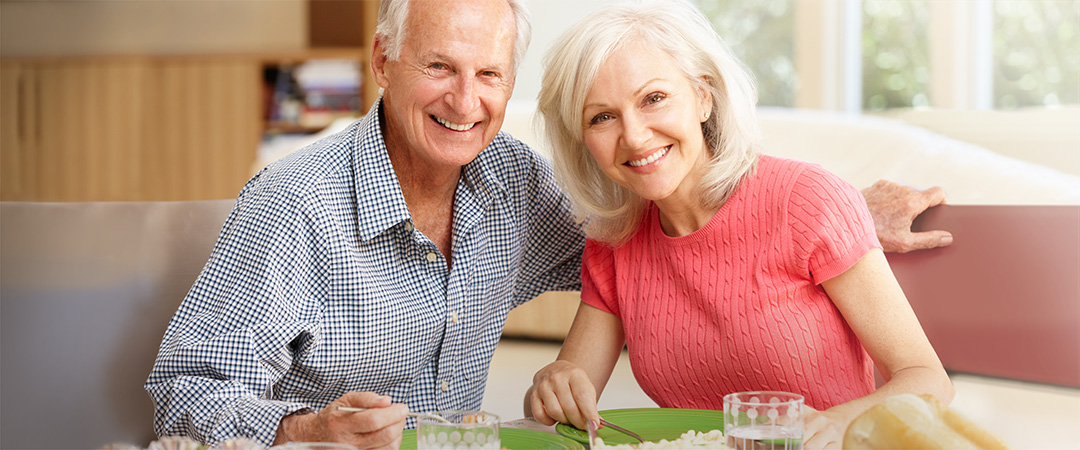 Elderly couple sitting at a table discussing downsizing for retirement