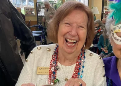 A resident laughing, wearing brightly colored beaded necklaces.