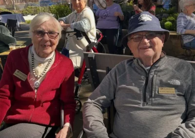 A senior couple sits outside at a facility event.