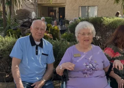 A senior couple sits outside at a facility event.
