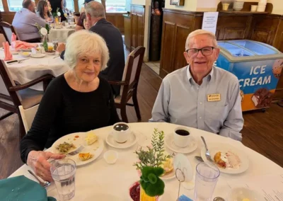 A senior couple sit together in the Sycamore Glen dining room, eating breakfast and enjoying coffee.