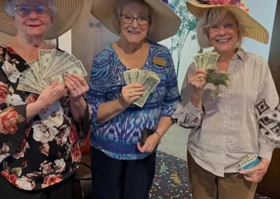 Three resident women in large straw hats show off dollar bills