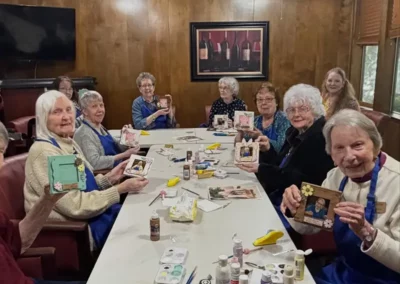 Residents sit around a table showing off photo frames they've decorated.