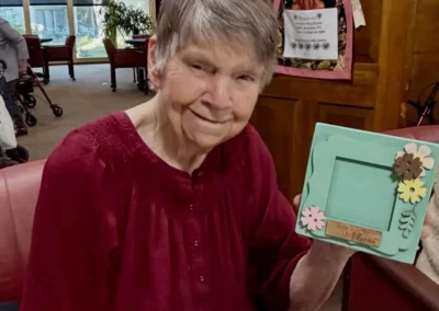 A resident shows off a photo frame she's decorated with wooden flowers.