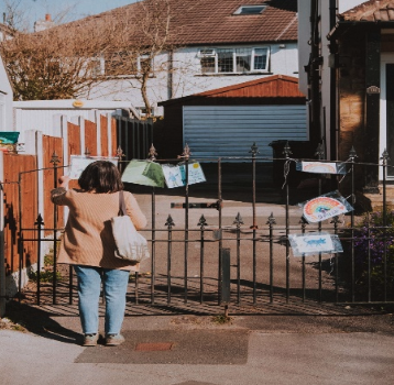 A woman at a gate viewing images that were taped to the gate.