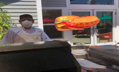 Staff Member With A Mask On Grilling Outside