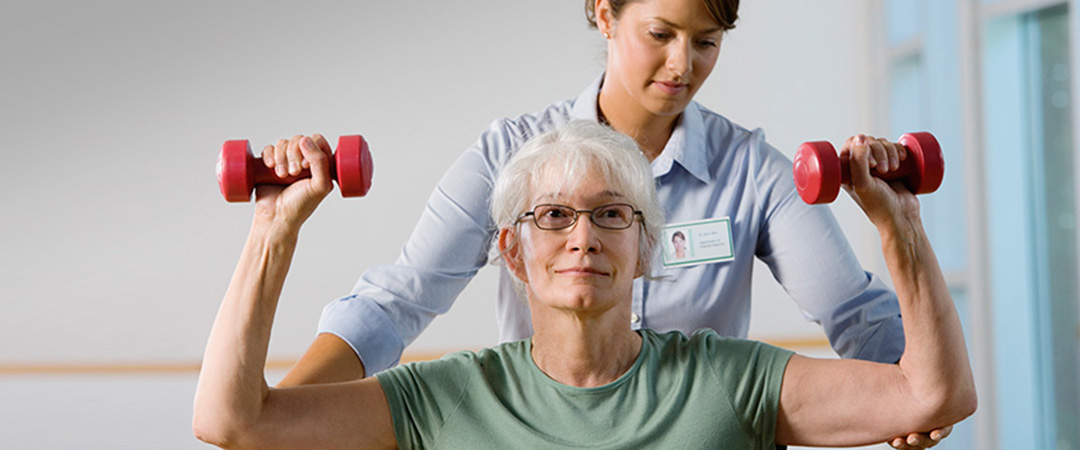 A senior and another woman performing dumbbell exercises together.