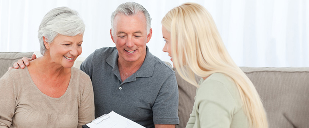 Two seniors and a woman going over paperwork together.
