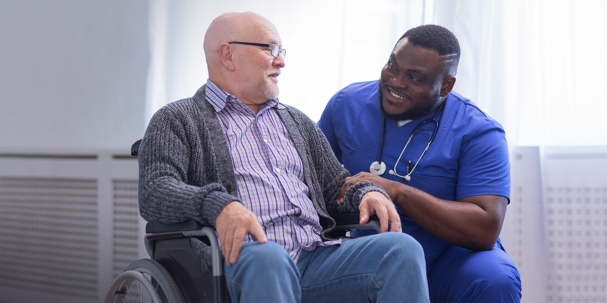 A nurse walking down the hall with a senior using a walker.