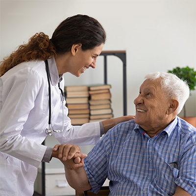 A nurse holding the hand of a senior in a wheelchair while they talk.