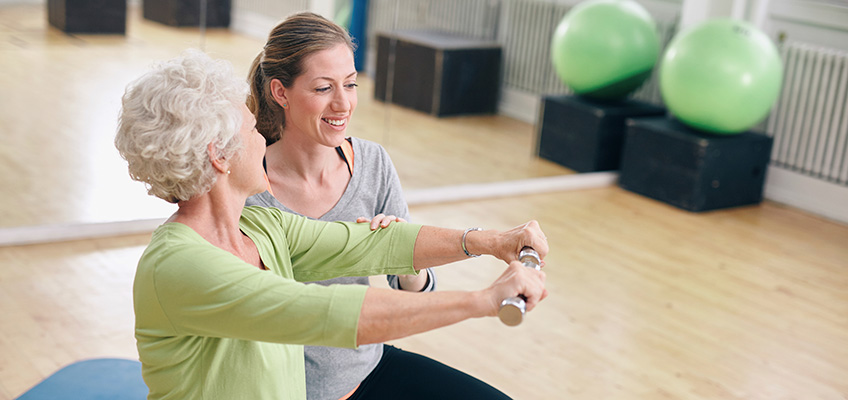 Therapist working with senior woman in a rehab gym.
