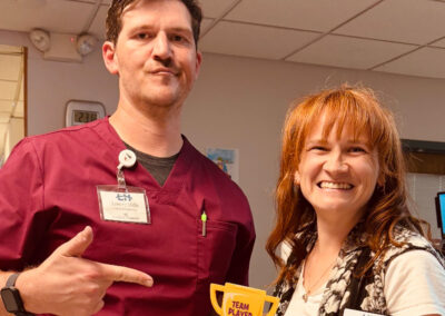 A nurse smiling with a woman holding an award at Lowry Hills