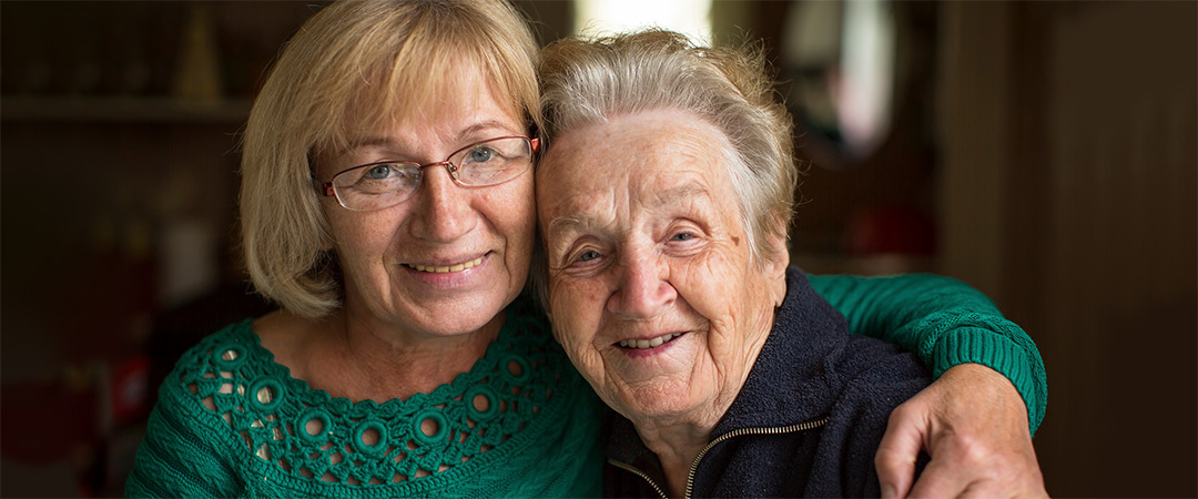 A smiling mother and daughter hugging each other.