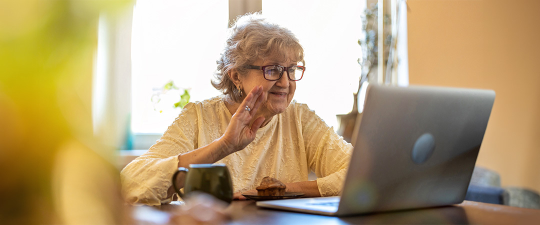 A senior woman on a lap top waving at the screen. A senior woman on a lap top waving at the screen.