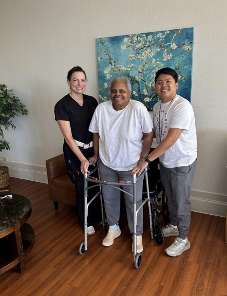 Evelyn in her walker with her rehab specialists who helped her recover.