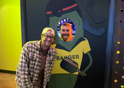 Two men standing by a pickle cutout at an event