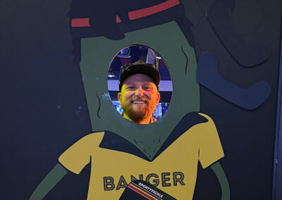 A man smiling behind a pickle cutout