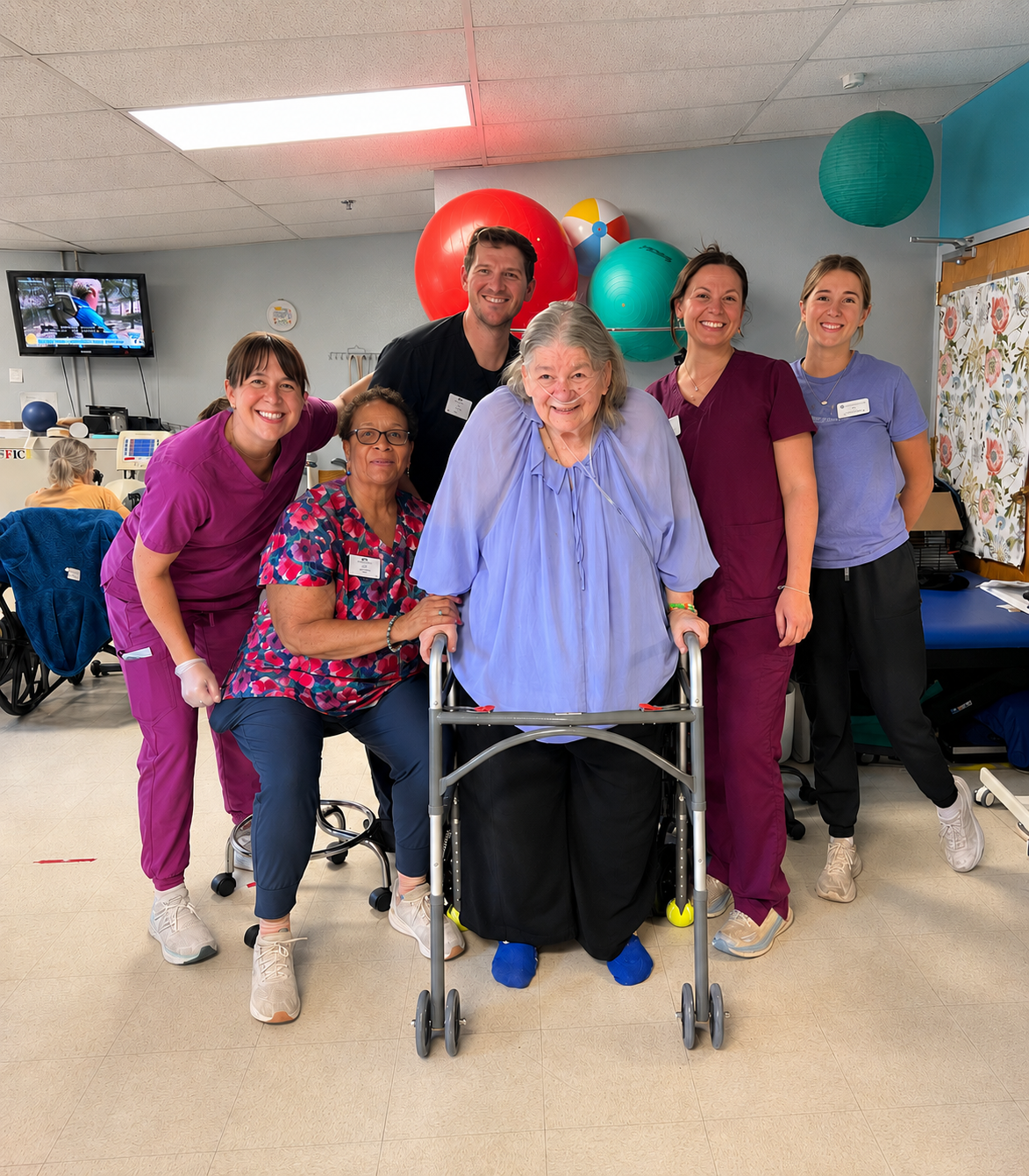 Woman with walker surrounded by her therapy team at Lowry Hills.