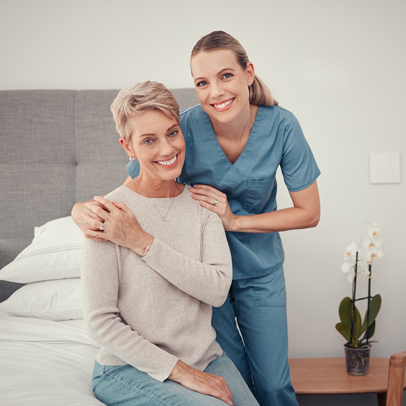 A nurse and a senior woman smiling together.
