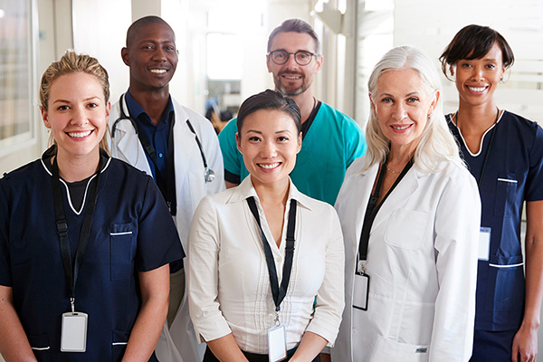 A group of men and women doctors and nurses smiling in a group.