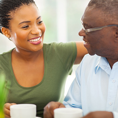 A senior and a young woman having coffee together while laughing.
