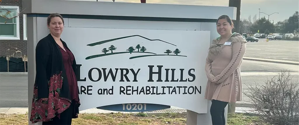 Two women standing in front of Lowry Hills outside sign.