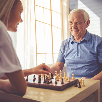 Caregiver playing chess with senior man.
