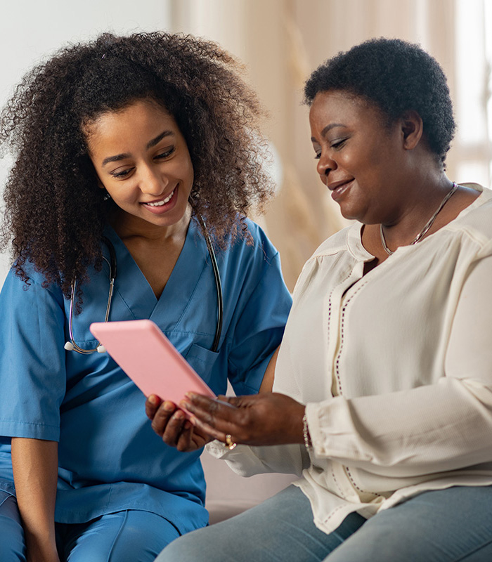 Healthcare worker looking at tablet with senior woman.