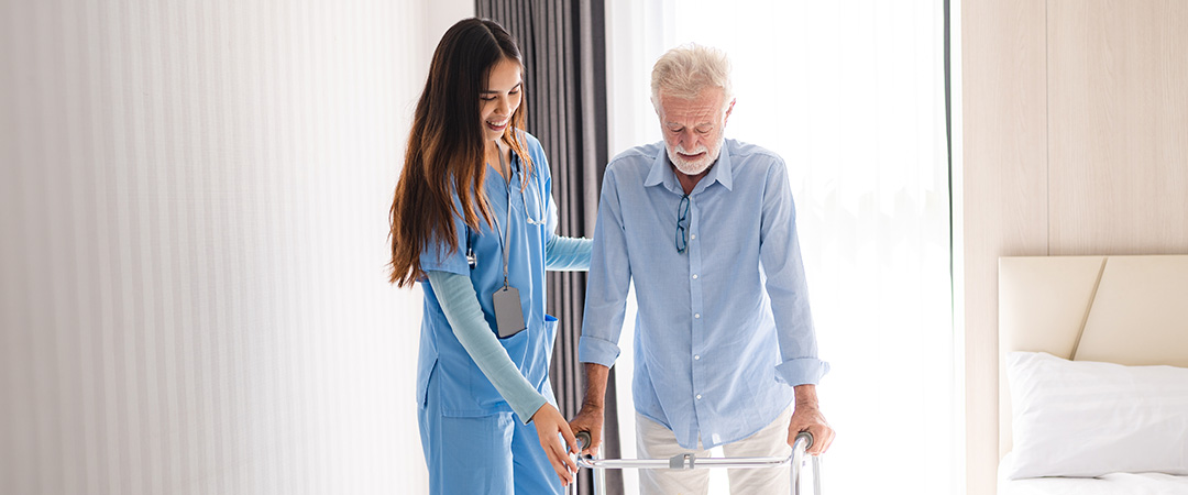 Healthcare worker helping senior man using a walker with fall prevention 