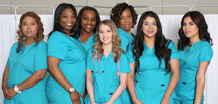 Several nursing dressed in blue scrubs gathered together