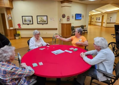 Four women playing Monopoly on a red circle table.