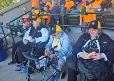 Two people in wheelchairs and two people with walkers at a baseball game with hotdogs