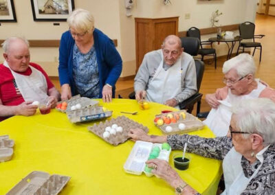 A group of residents painting eggs at an activity at Elm Crest