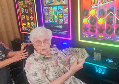 An elderly woman holding money at a slot machine at Elm Crest