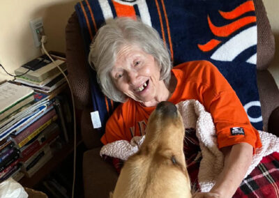 An elderly woman smiling with a dog at Elm Crest