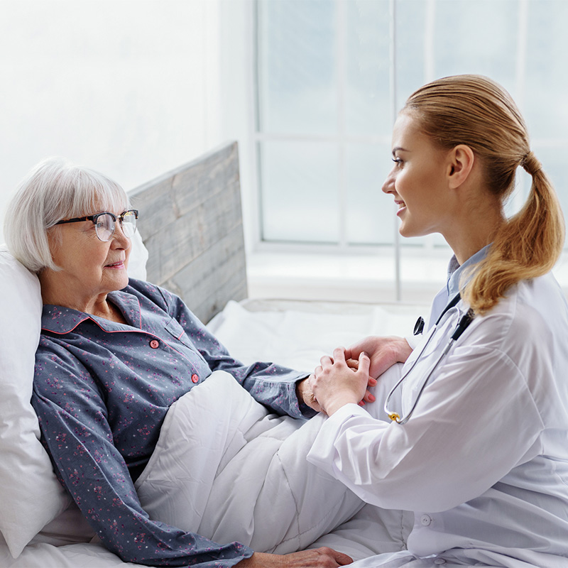 Female medical professional holding a residents hand while they are talking.