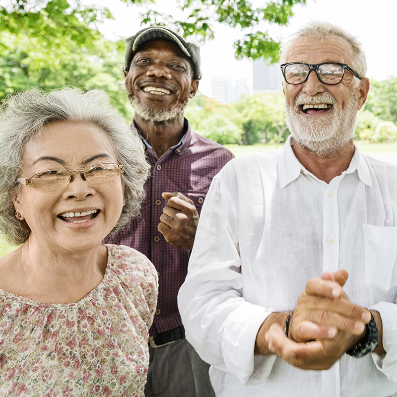 three senior residents standing outside while smiling and clapping