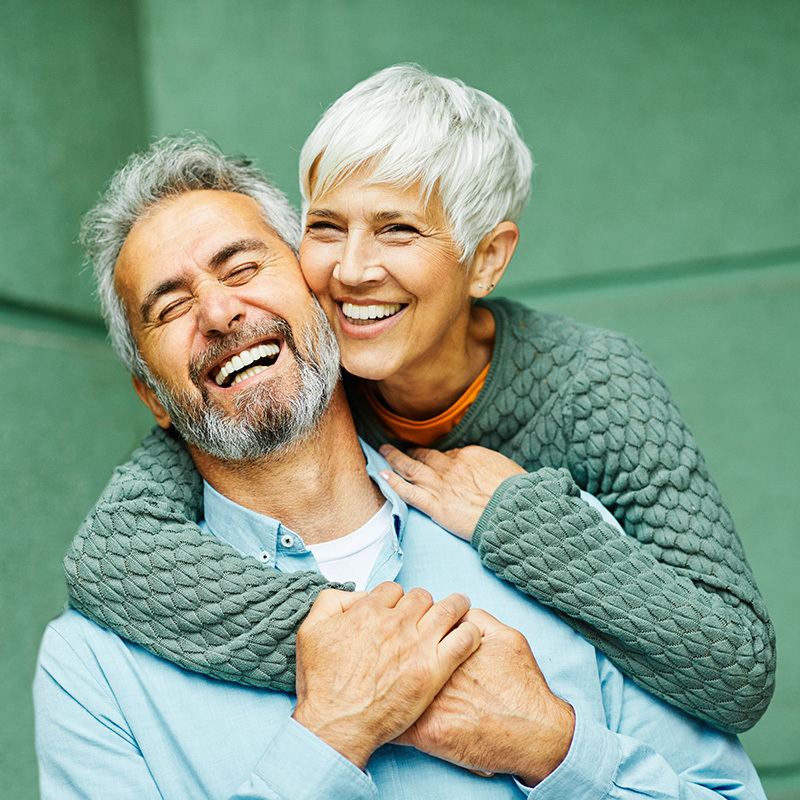 A mature couple smiling together as they embrace each other.