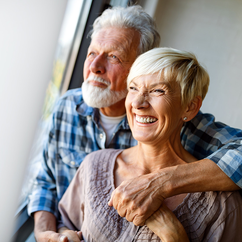 A senior couple looking outside while holding hands.