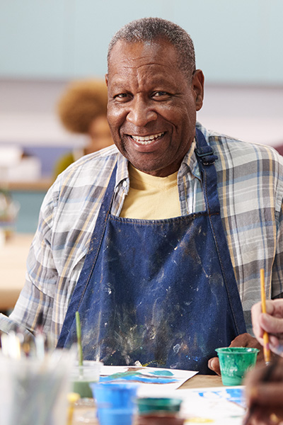 A mature male outside painting with other seniors.
