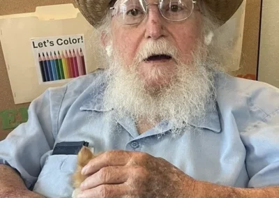 Older man wearing straw hat and holding kitten.