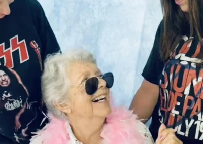 Older woman in pink boa next to two young women with Kiss t-shirts.