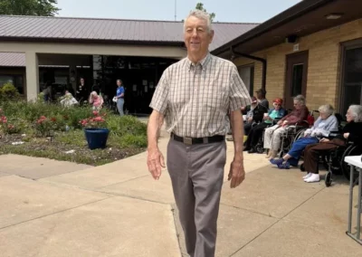 Older man walking outside in courtyard.