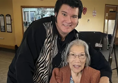 An Elvis impersonator with Peggy seated, both smiling