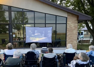 several seniors some in wheelchairs are watching an outdoor movie