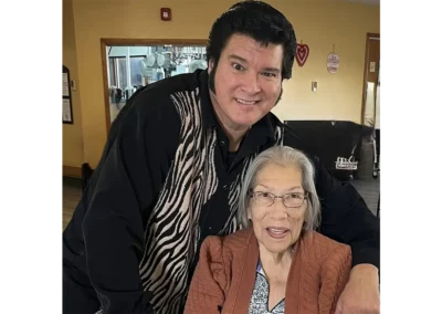 An Elvis impersonator with Peggy seated, both smiling
