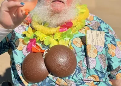 A resident sitting outside with a lei and coconuts, holding a water balloon